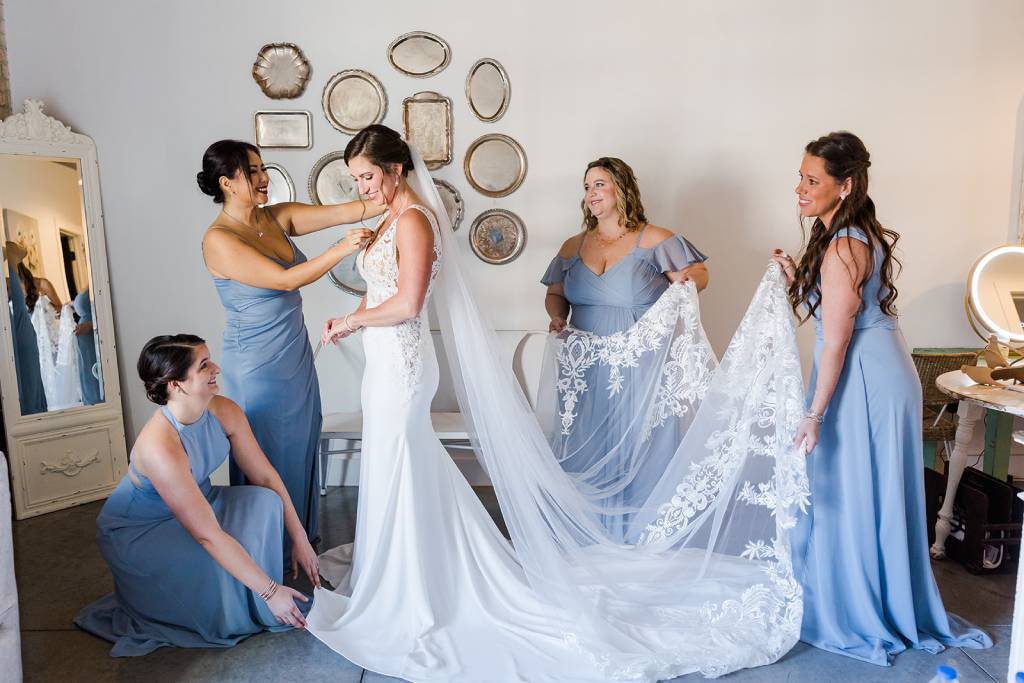 A beautiful bride gets ready for her wedding day, her party dressed in pastel bridesmaid dresses of sky-blue.
