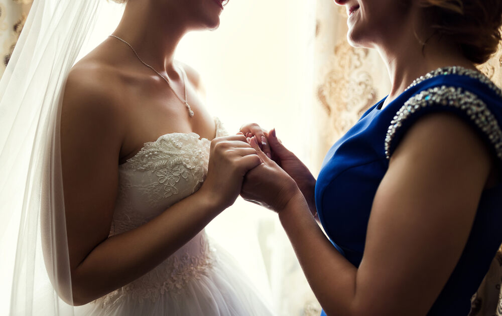 Bride and mother, holding hands on a wedding day.